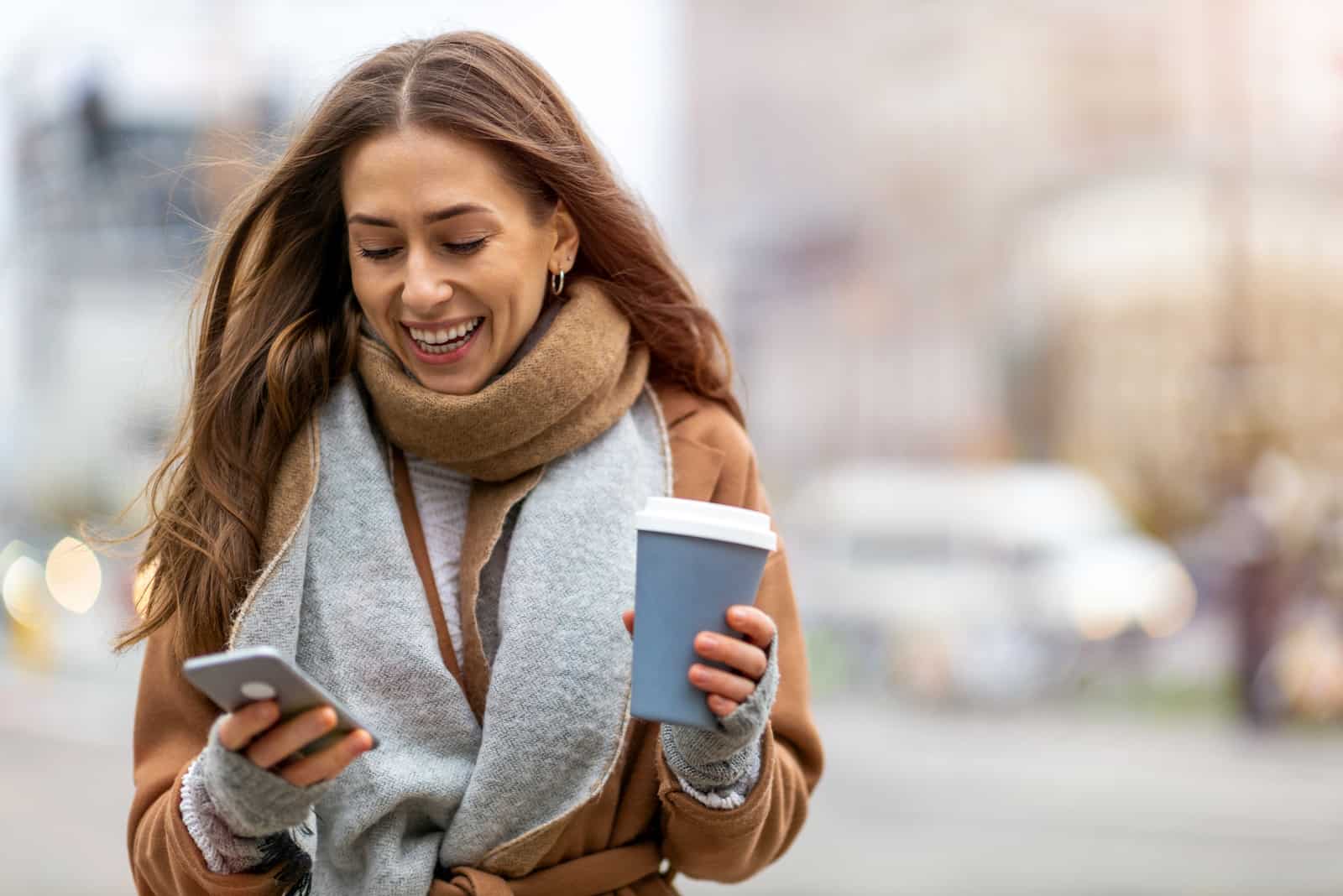 una donna sorridente cammina per la strada e attacca bottone al telefono