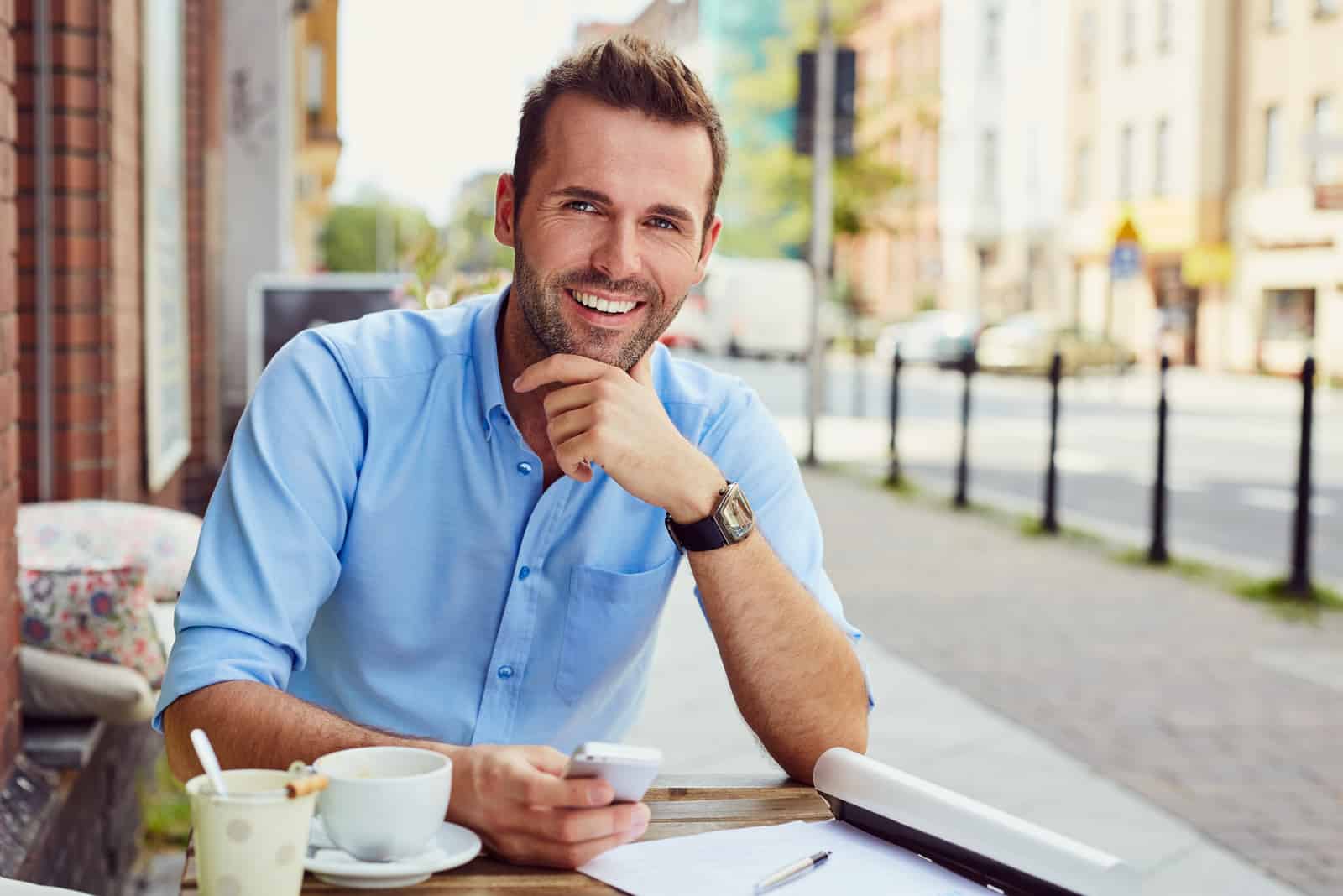 homem atraente sentado num café ao ar livre