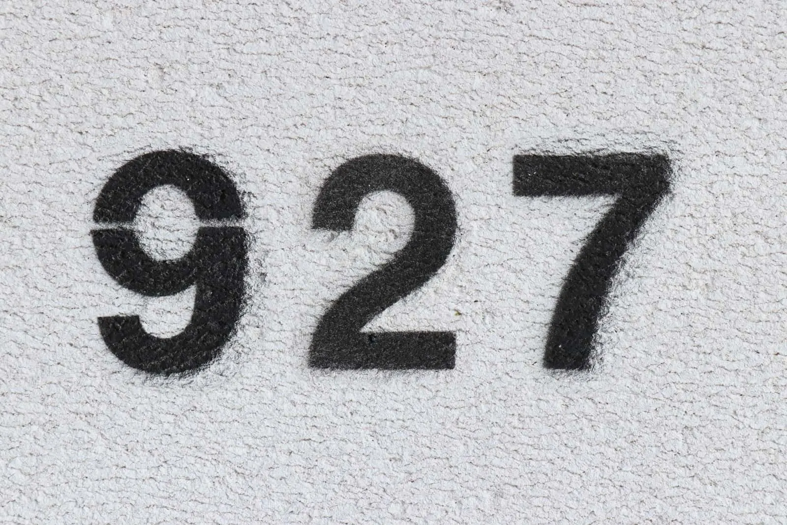 black number 927 on grey wall
