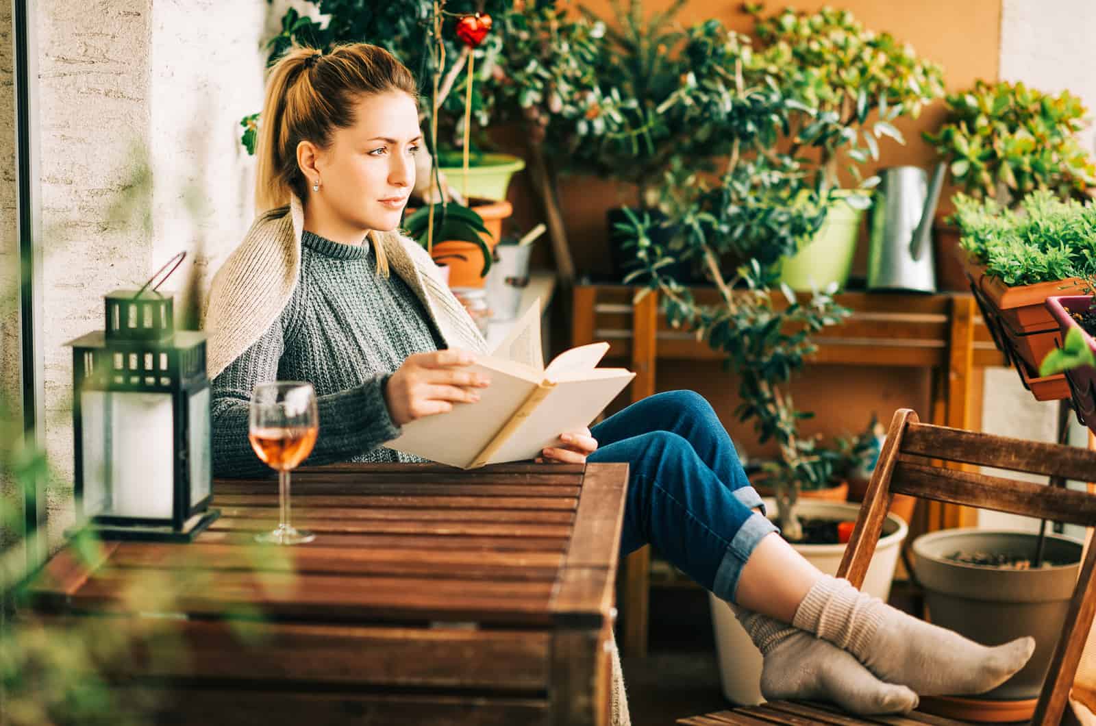 blonde woman reading a book and drinking wine