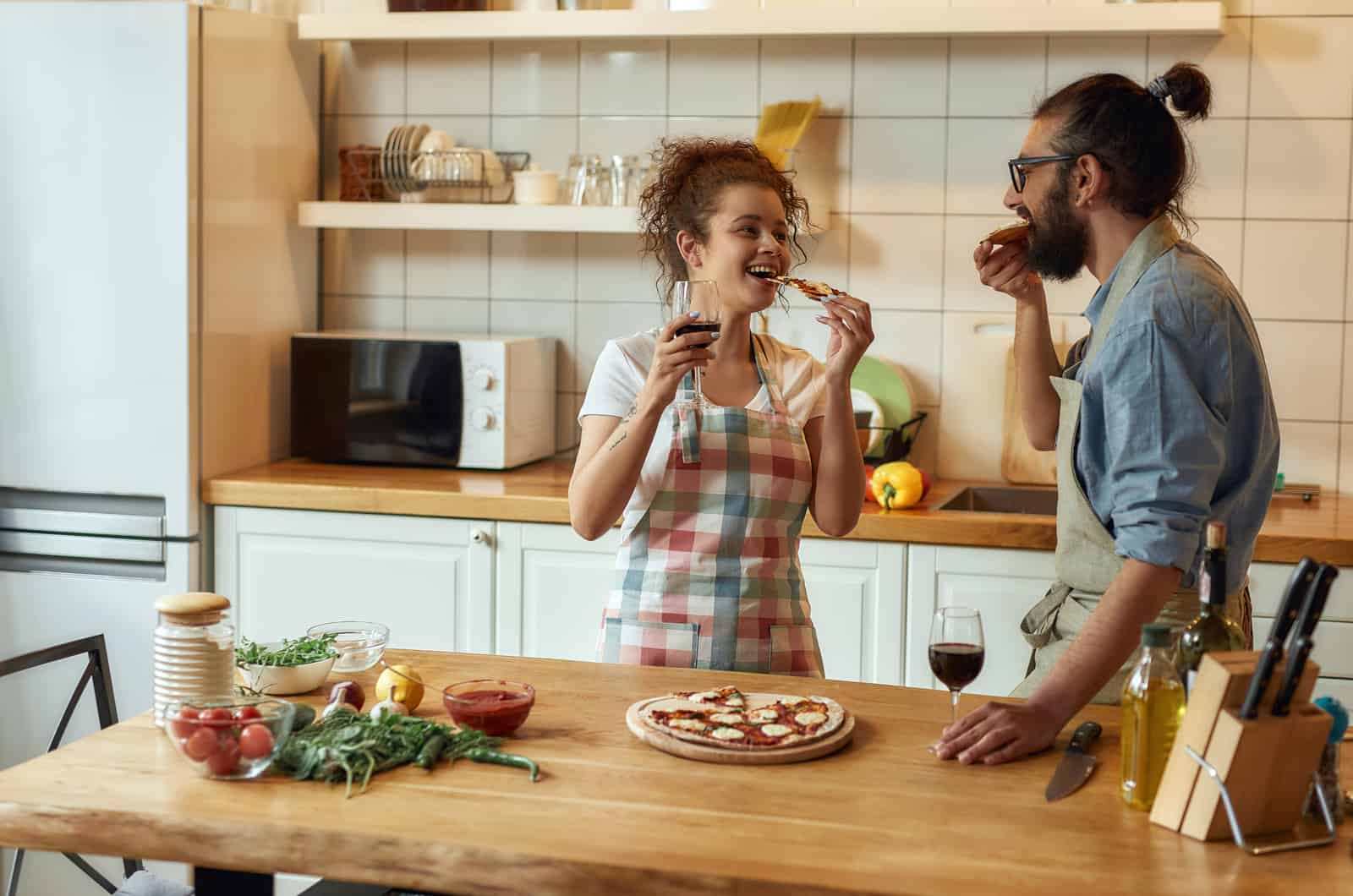 pareja feliz en la cocina hablando y comiendo pizza