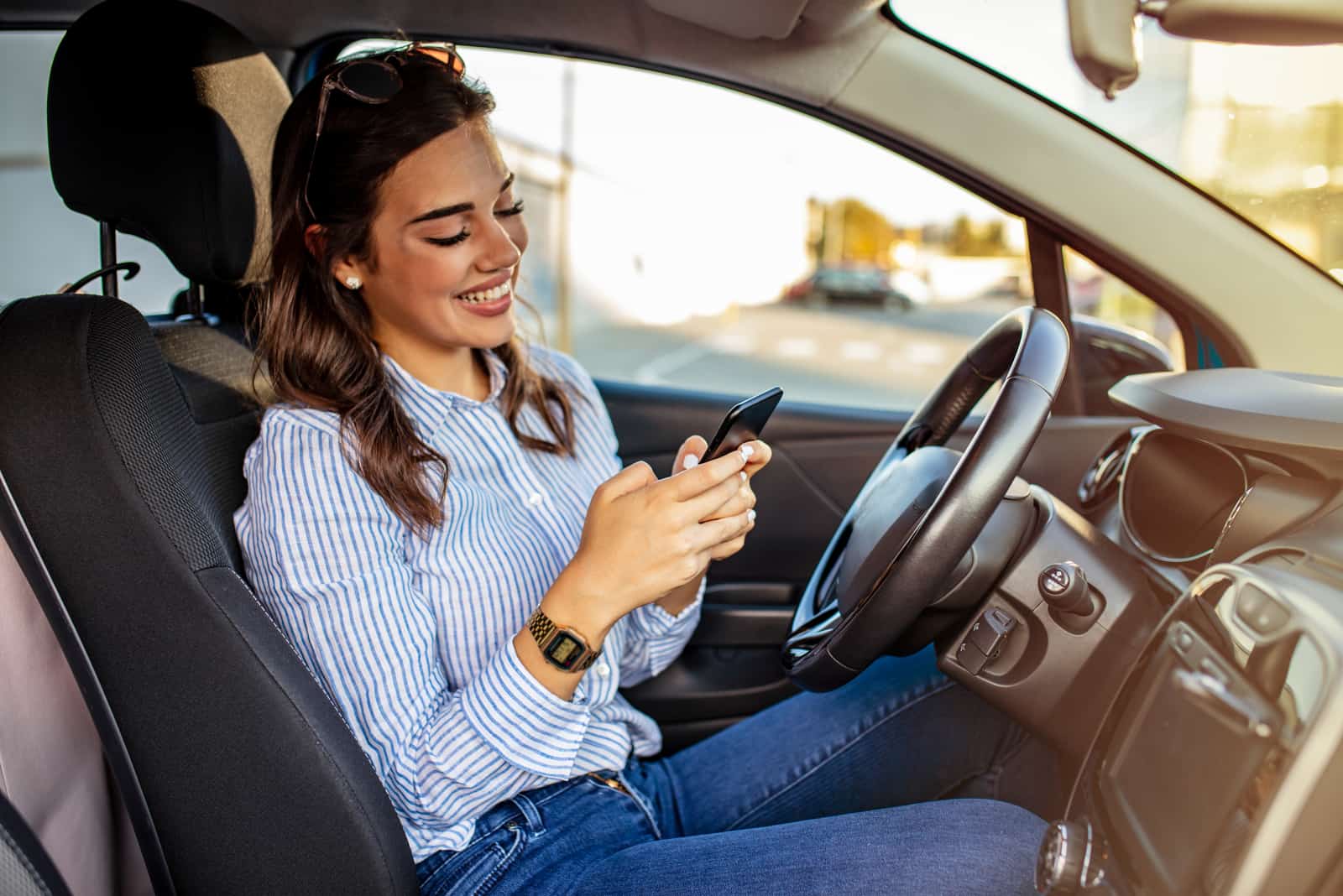 donna felice seduta in auto che legge i suoi messaggi