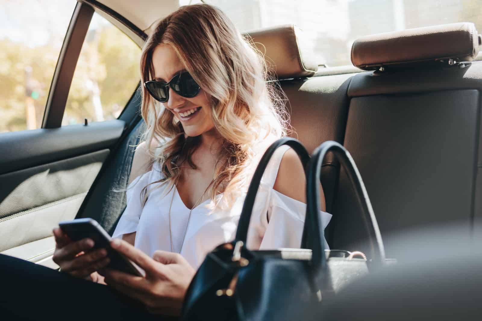 happy woman texting her friend while riding in car