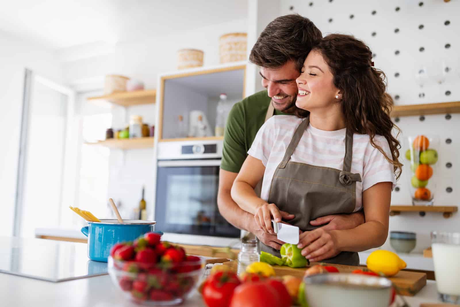 man hugging woman who is cooking from behind
