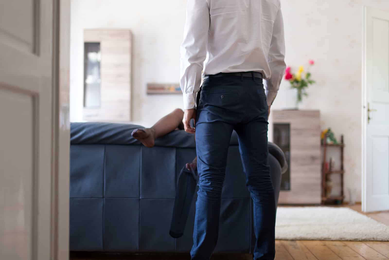 man in suit standing in front of sofa with woman on it