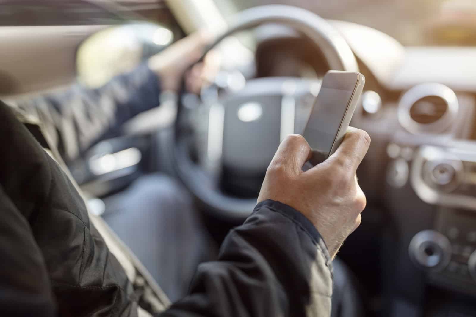 man reading his messages on his phone while driving