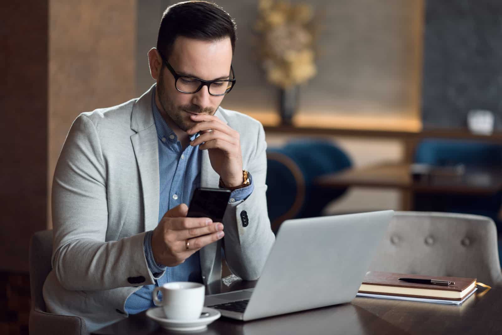 uomo seduto in un caffè che legge i suoi messaggi