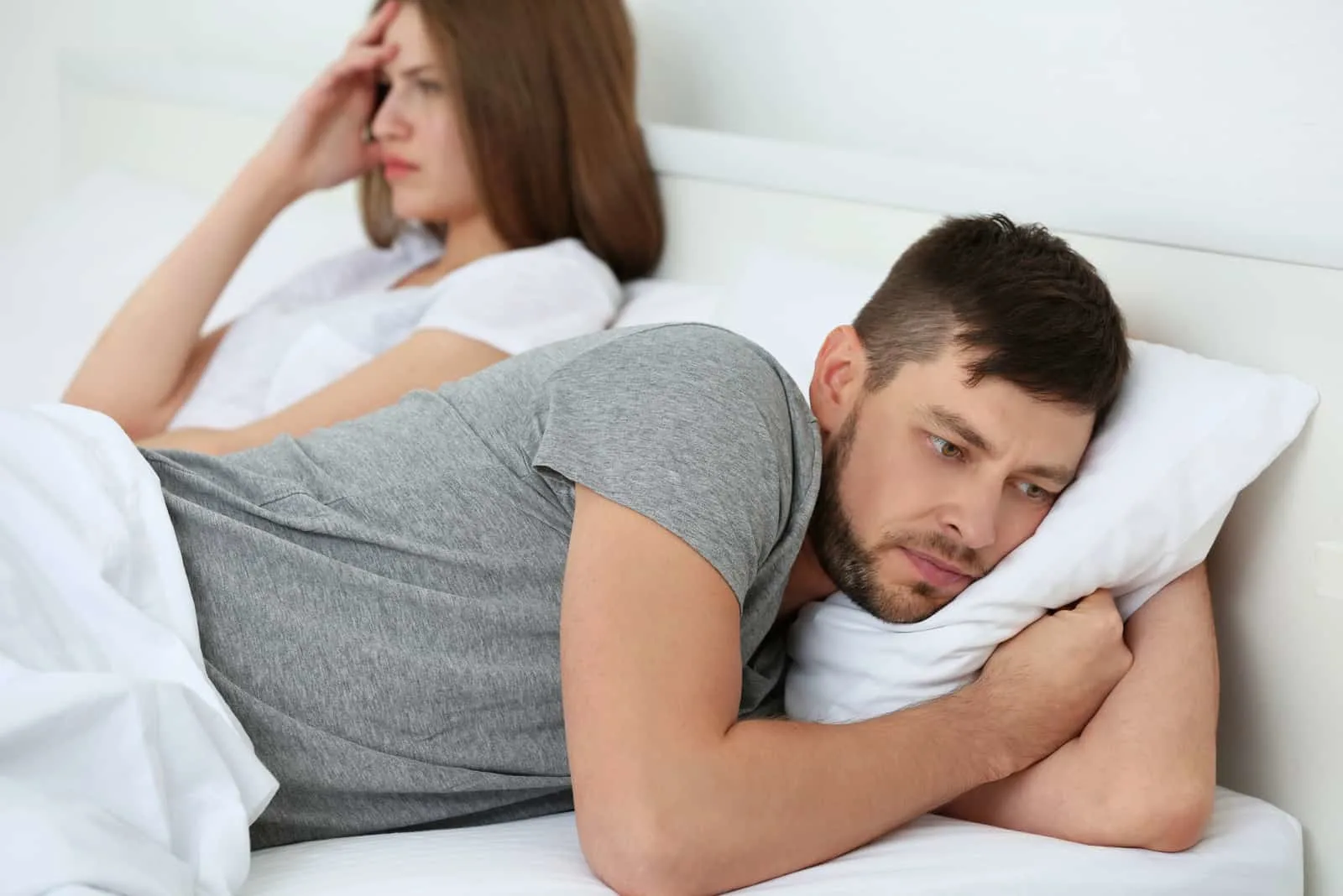 man turning his back to his wife in bed