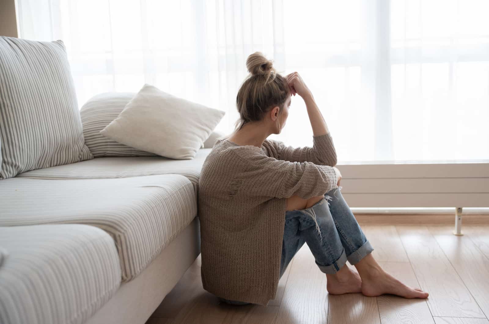 joven triste sentada en el suelo del salón