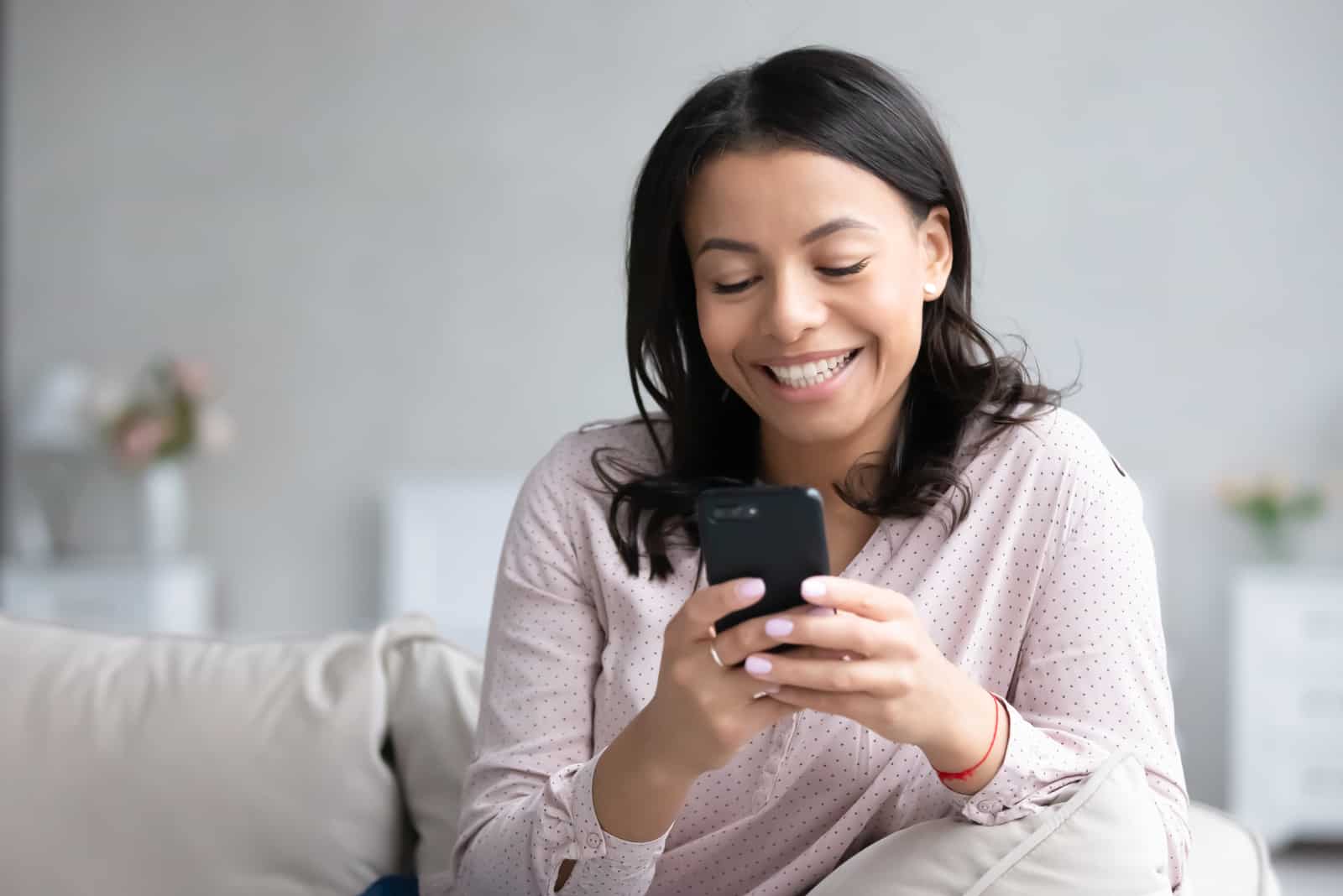 smiling woman sitting on sofa texting