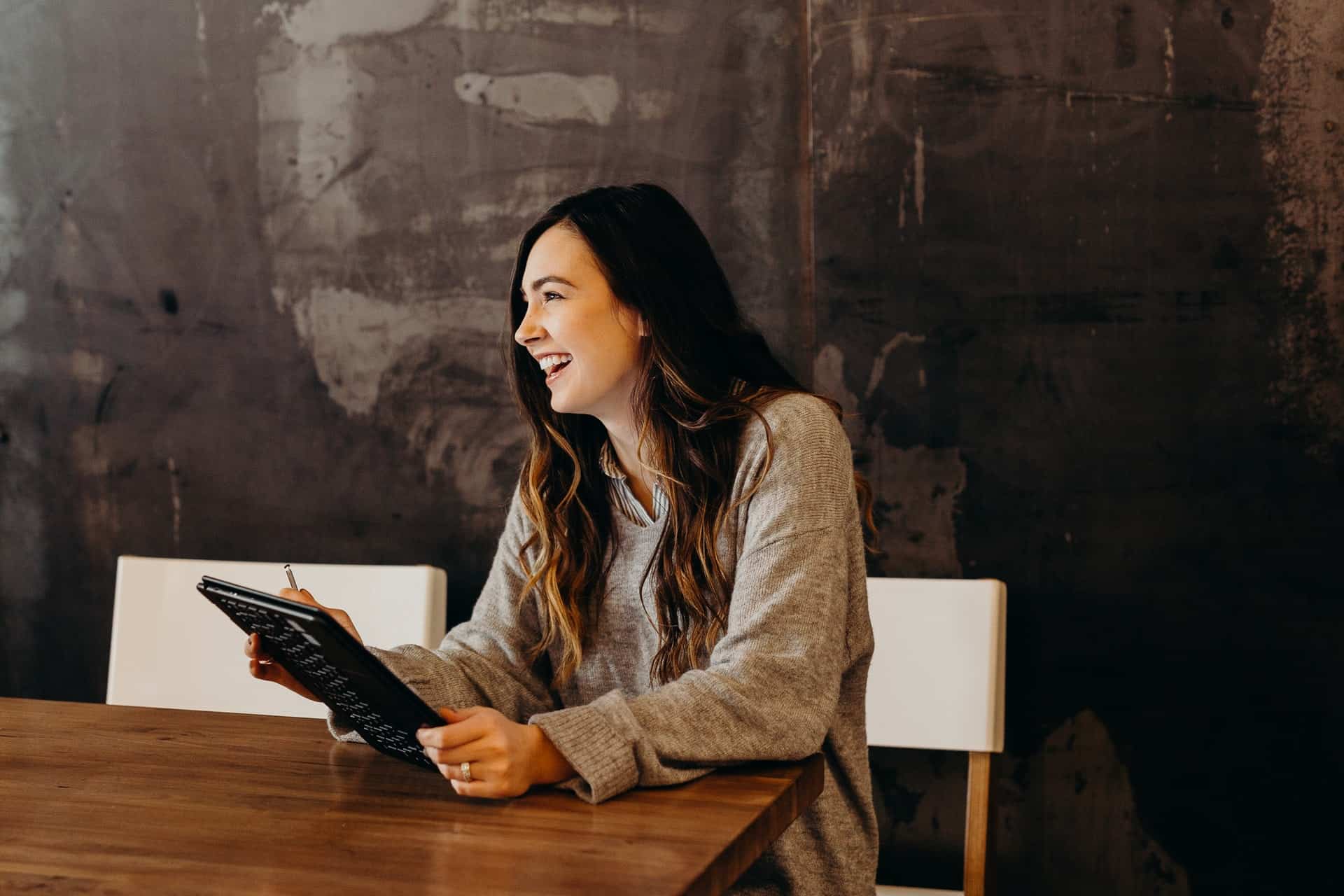 woman holding a tablet and laughing