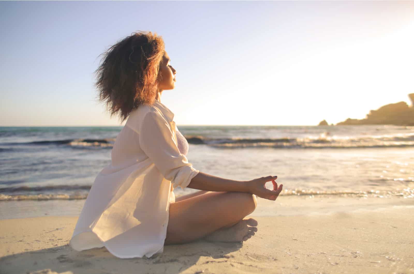 mulher a meditar na praia em suset