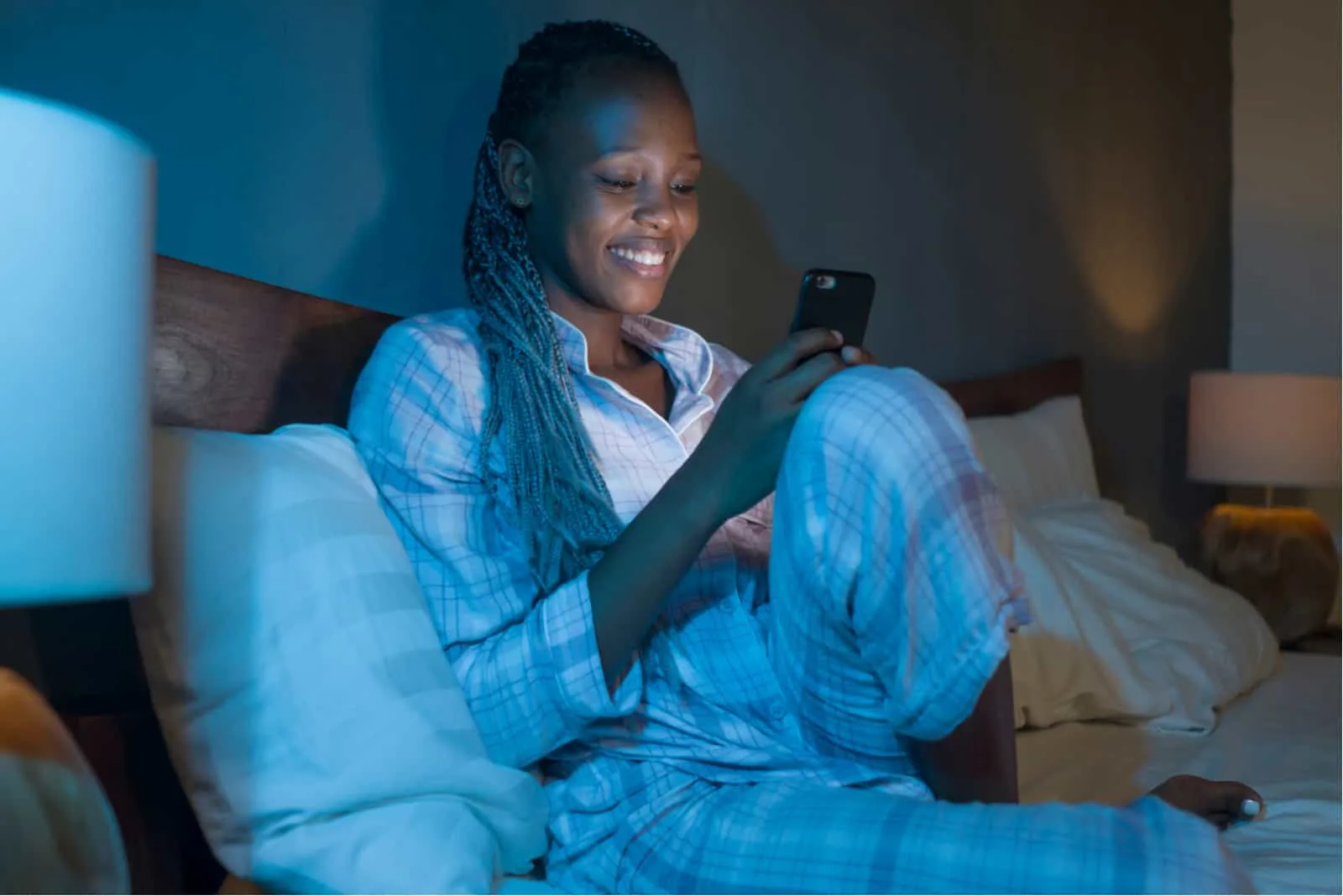 woman sitting on her bed with phone in hands