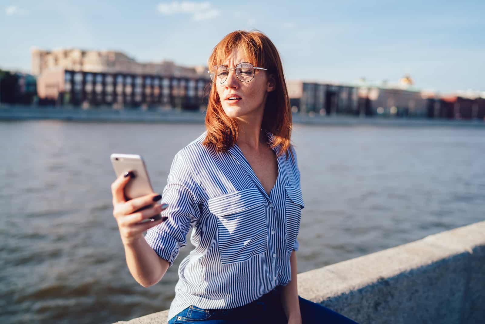 woman standing outside looking at something on her phone