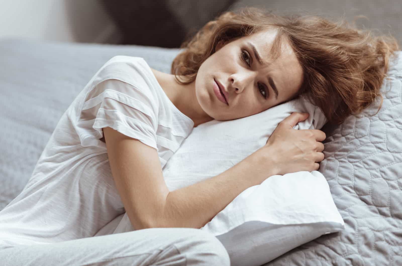 worried woman hugging pillow indoors