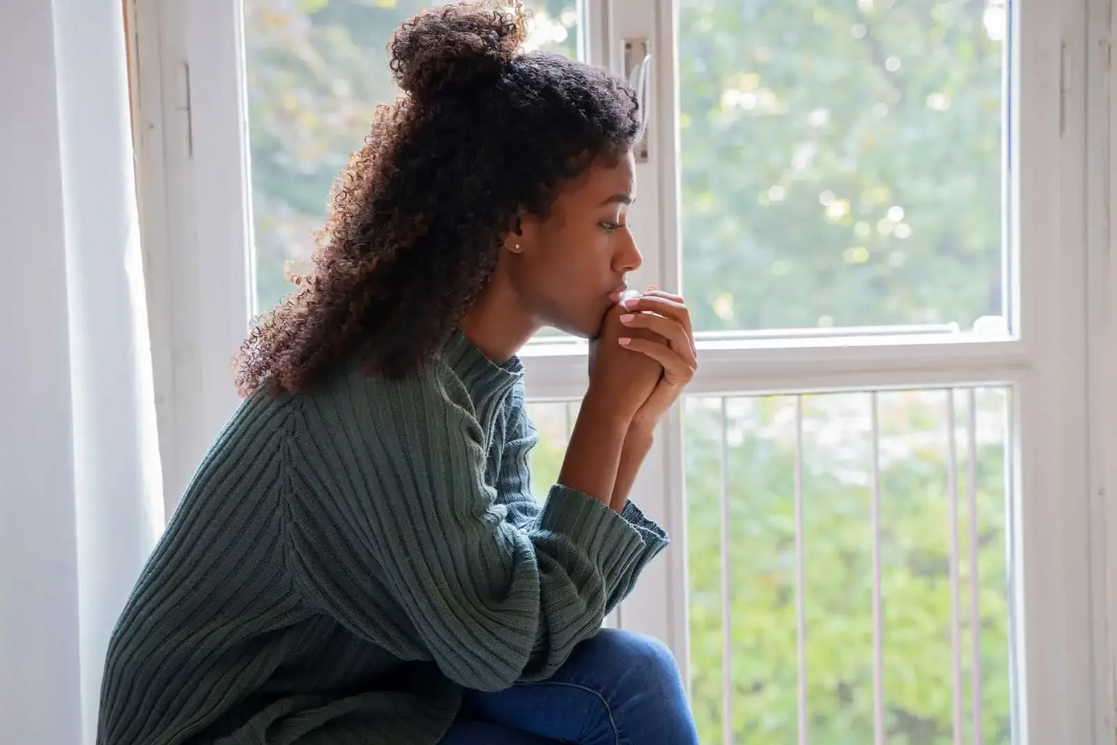 young girl sitting by window praying