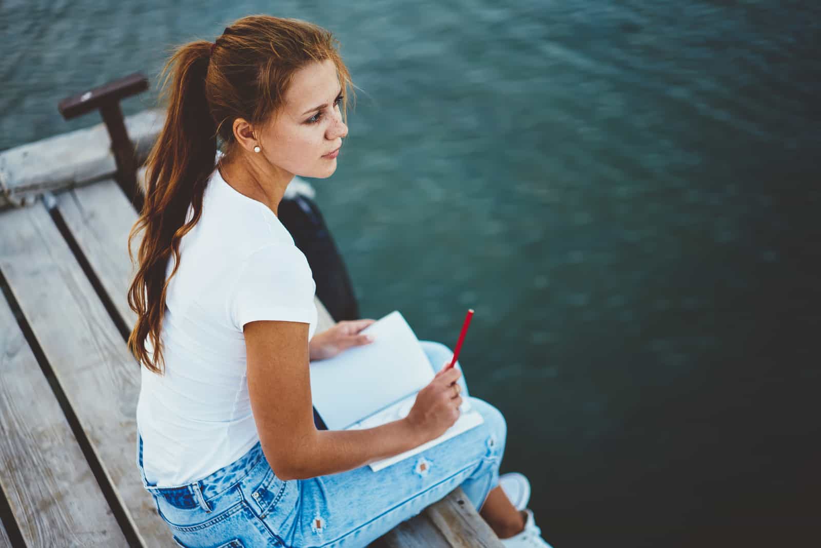 young girl sitting on dock by lake