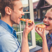 Beautiful young couple is eating pizza