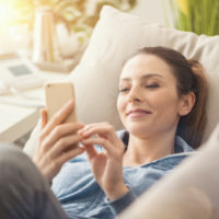 woman texting while lying on sofa