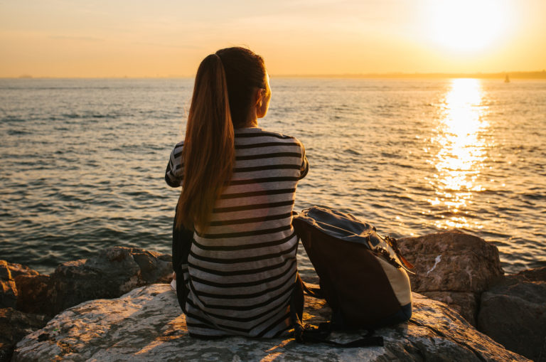 womans itting on rock by sea