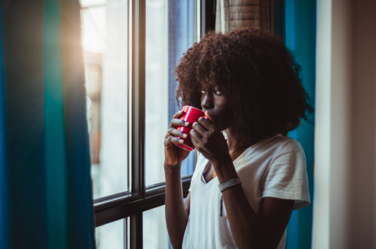 girl drinking coffe and standing by window