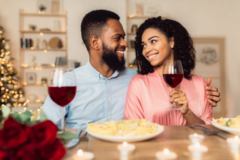 a smiling loving couple sitting at a table embracing