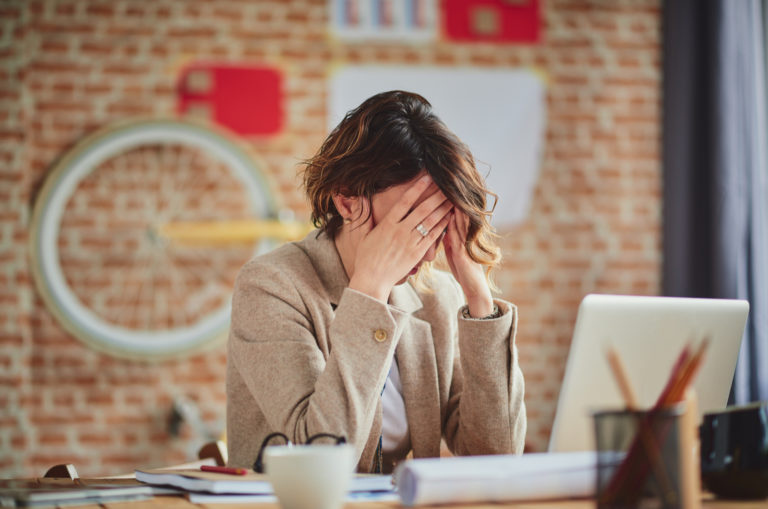 tired woman covering her face at work