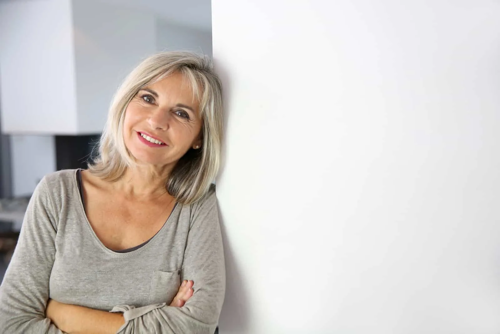 Senior woman standing against white wall