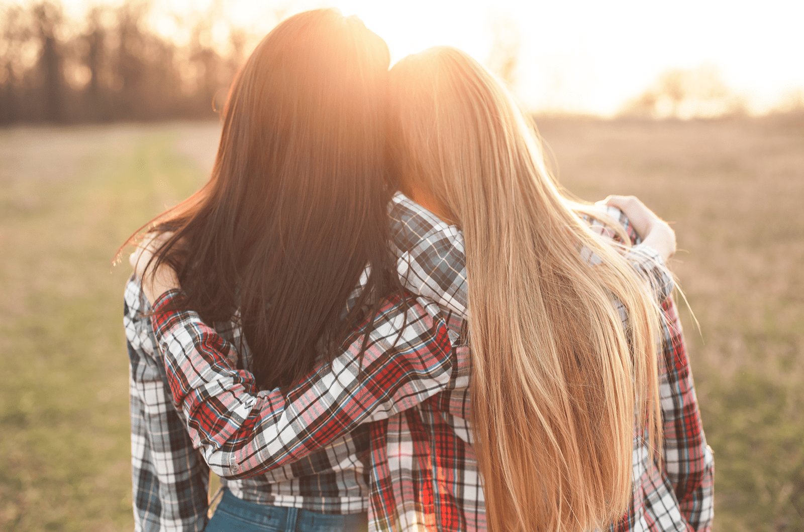 Due giovani donne guardano il tramonto e si abbracciano