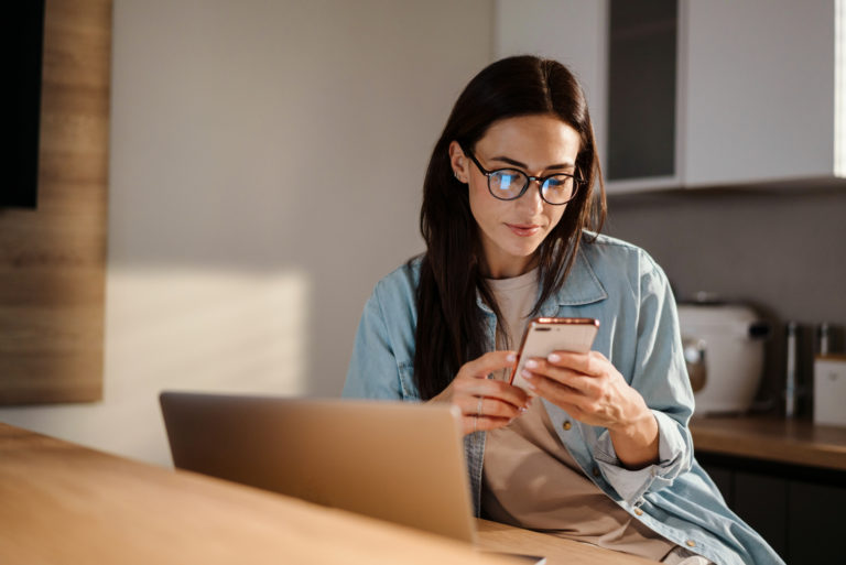 a woman with dry black hair sitting at a table and pressing a button on the phone