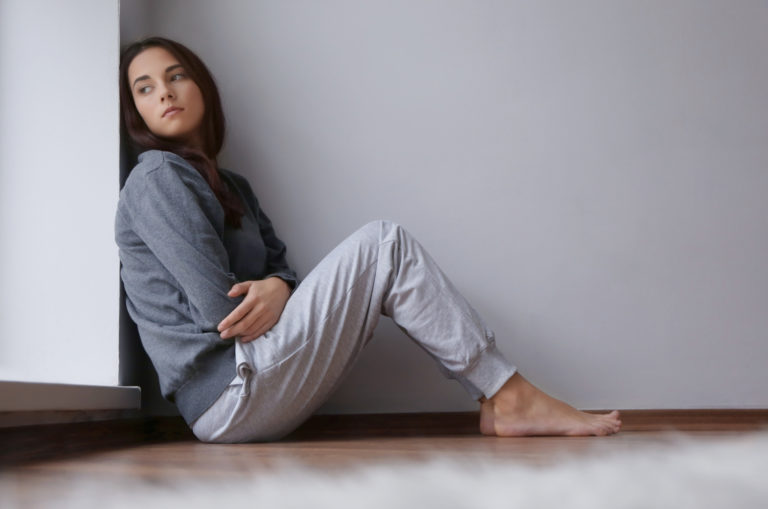 sad young woman sitting on the floor