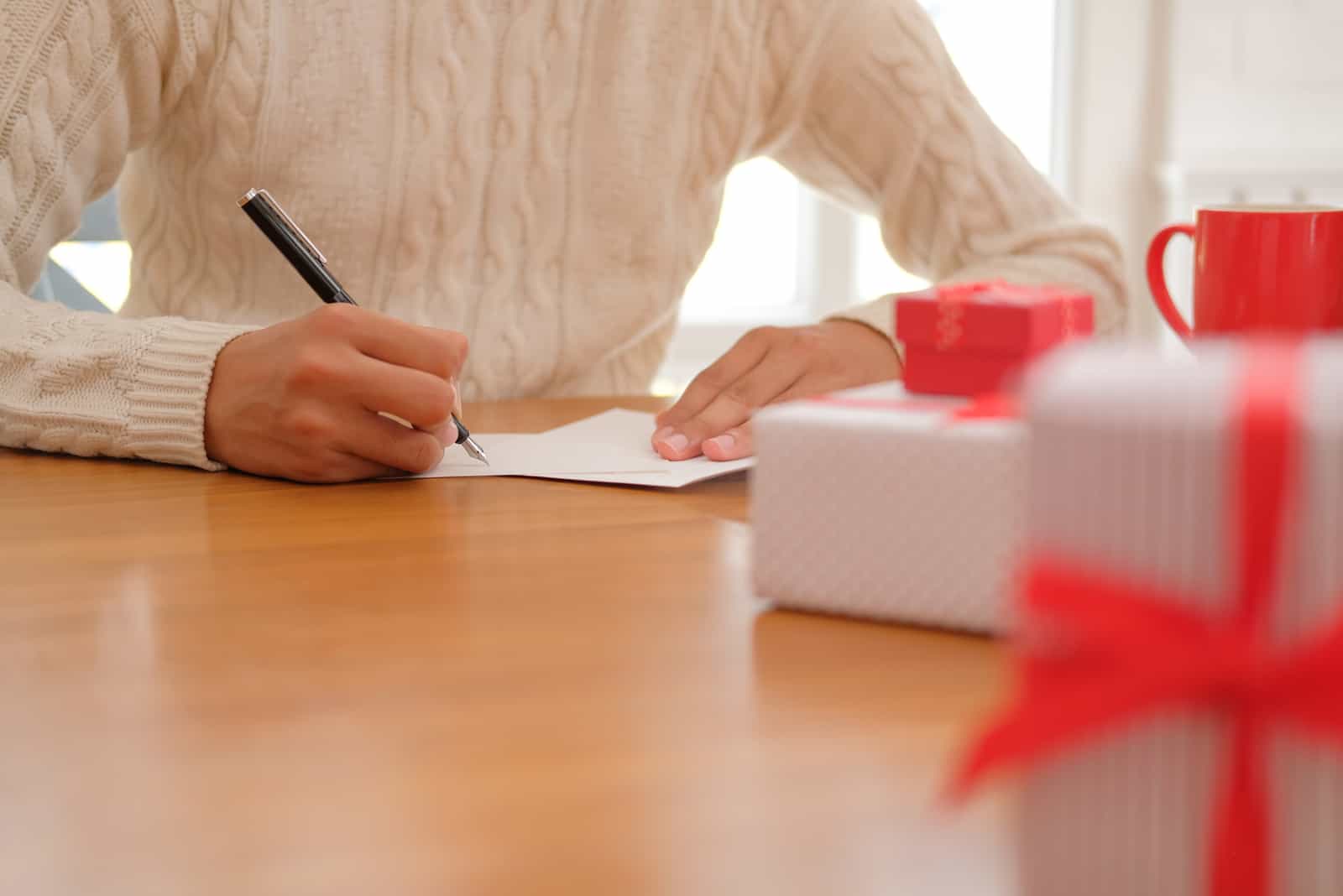 un hombre se sienta a la mesa y escribe una tarjeta de felicitación