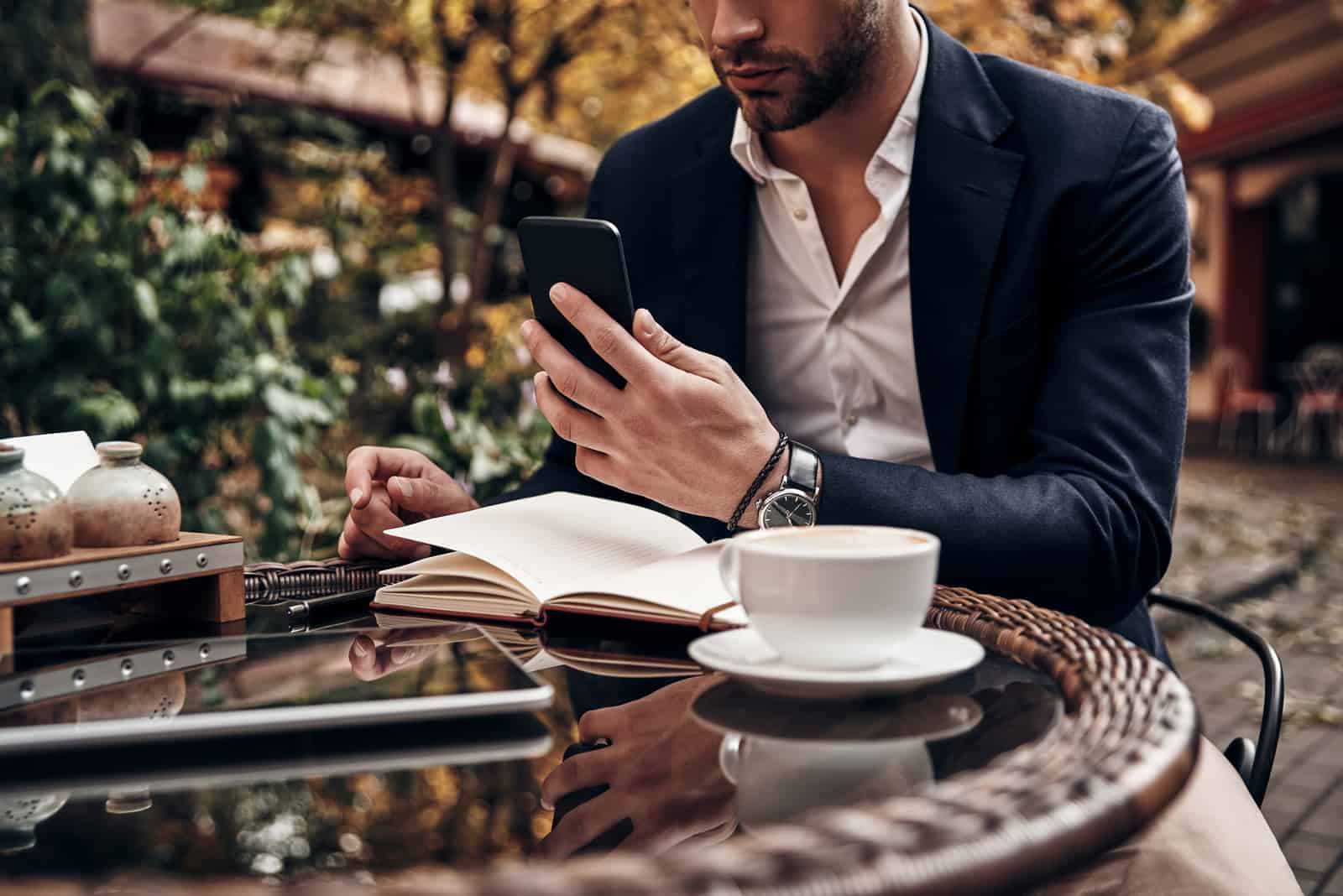 un uomo seduto a un tavolo all'aperto e un pulsante sul telefono