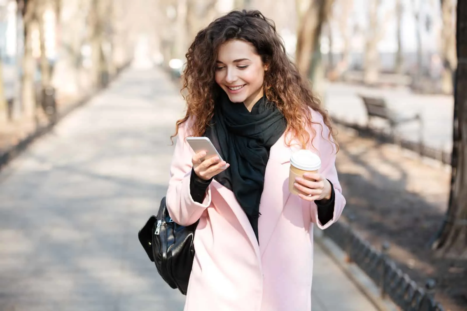 a smiling woman with frizzy hair stands on the street and buttons on the phone