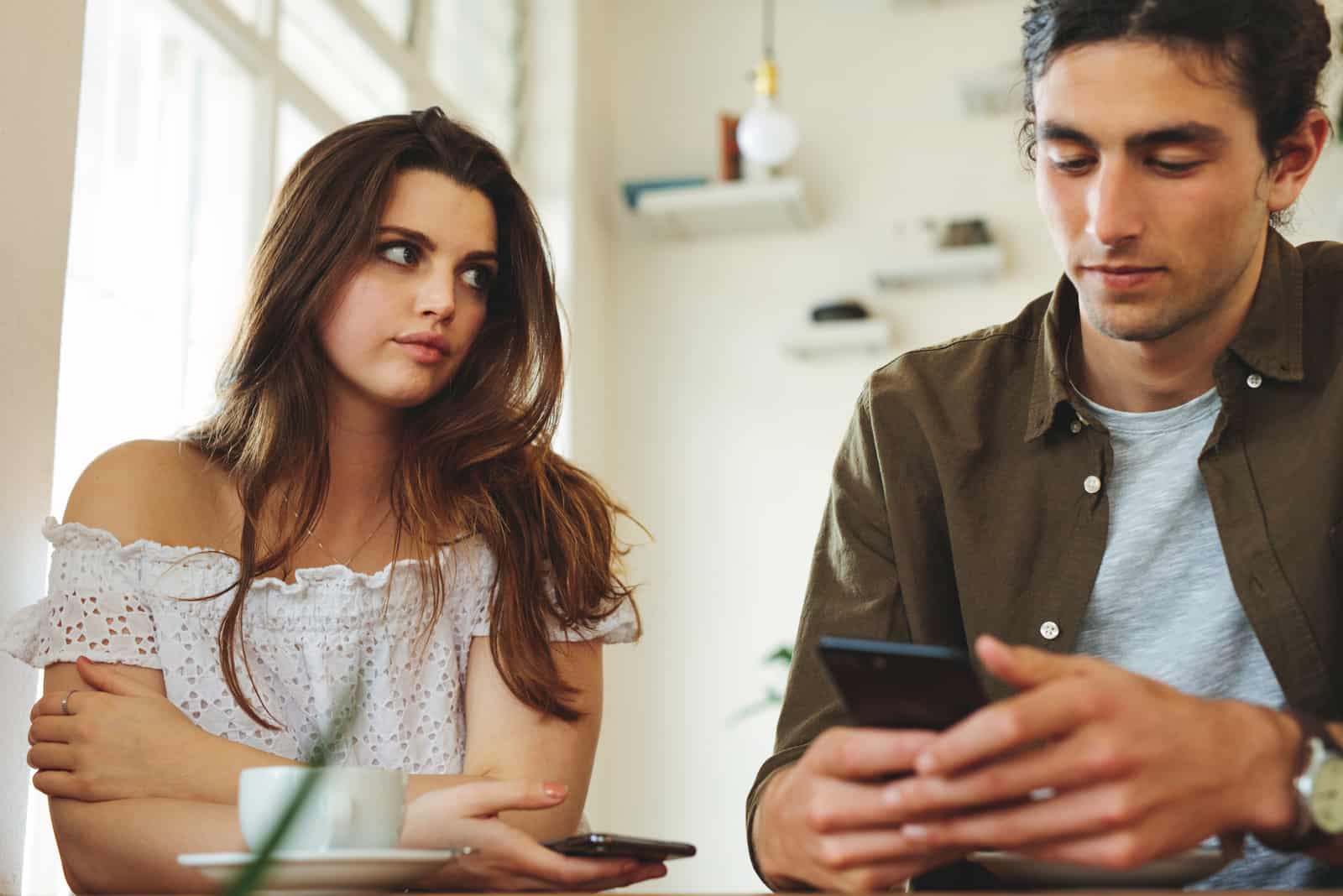 a woman looks at a man while he is typing on the phone