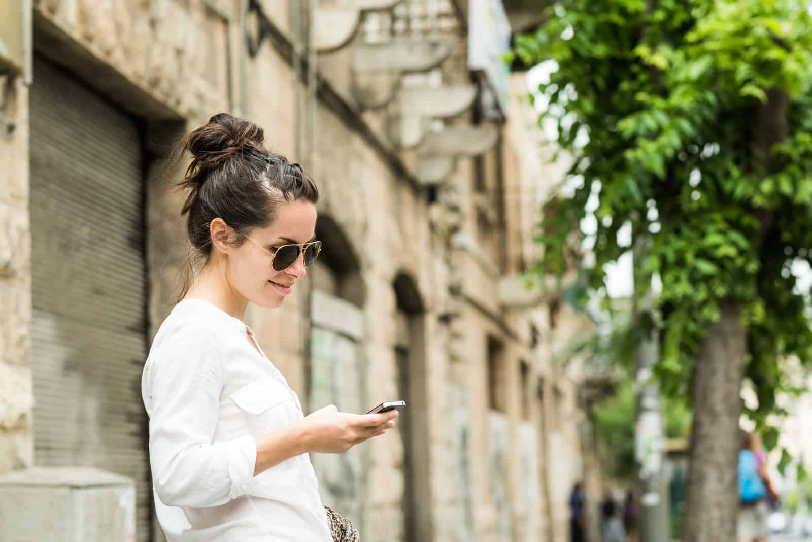 a woman with tied hair stands on the street and a button on the phone