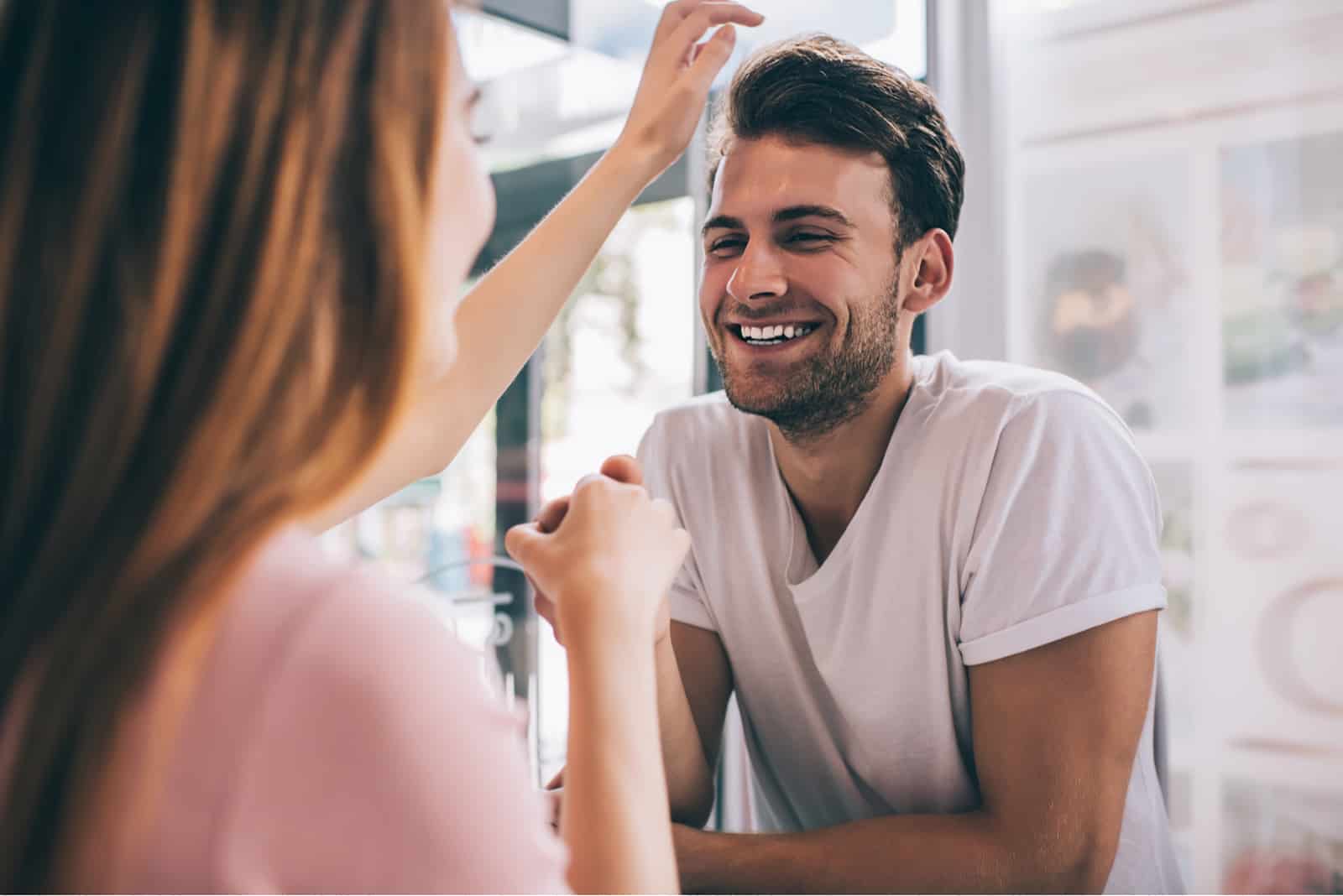 laughing romantic man in love holding hand of partner during flirting 