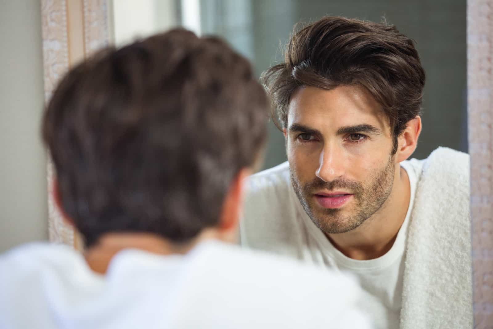 man looking himself in mirror