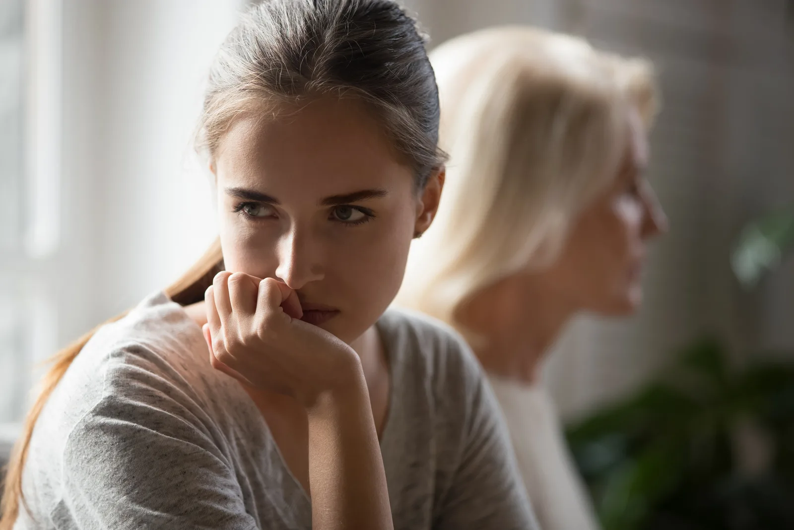 offended young woman looking at distance while sitting next to mother in law