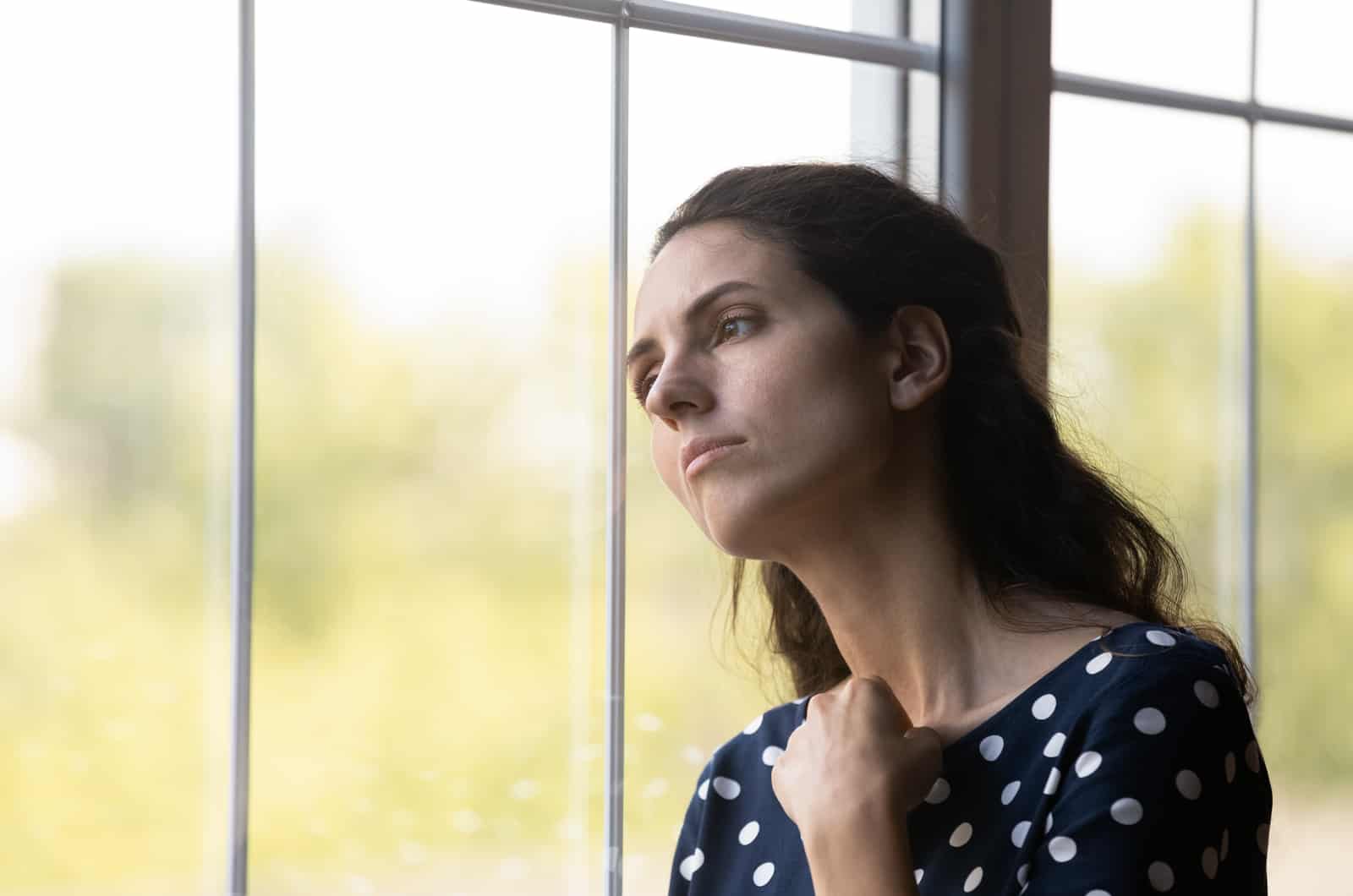 sad young woman looking through window