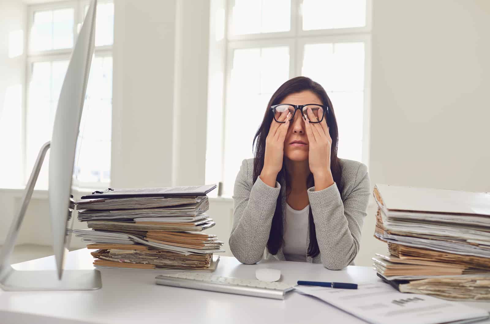 tired woman rubbing her face in office