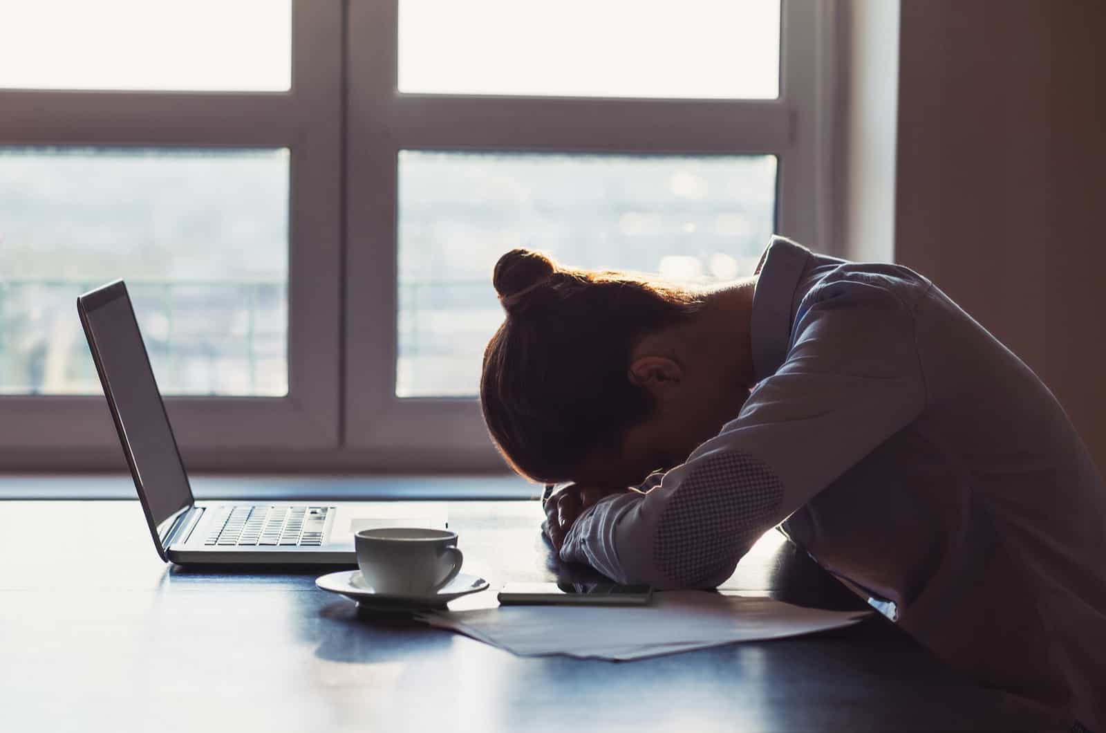 mulher cansada a dormir na secretária do trabalho