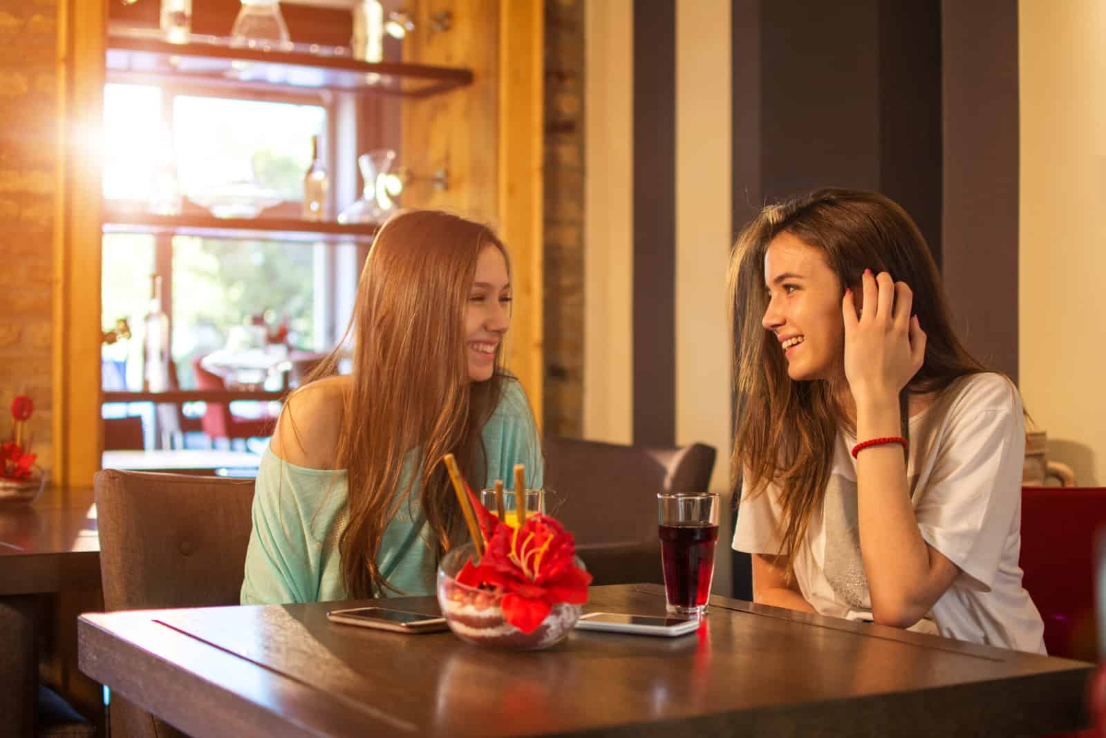 two young girls talking in cafe
