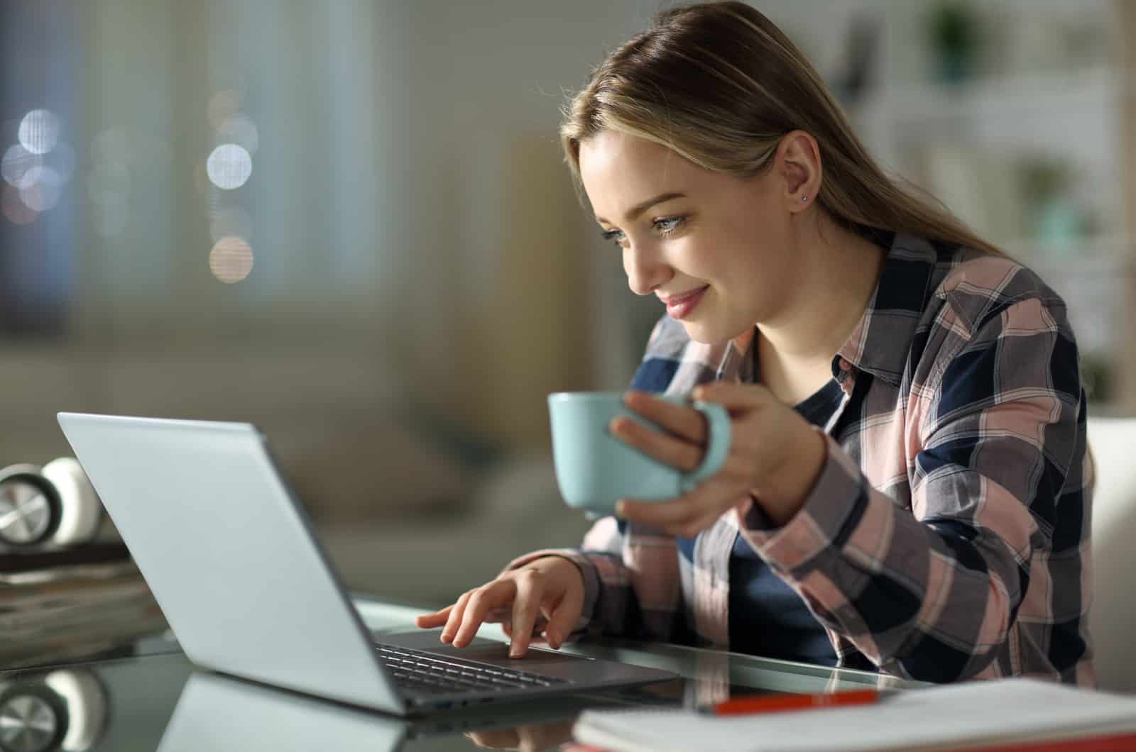 mujer con un portátil y una taza de café en la mano