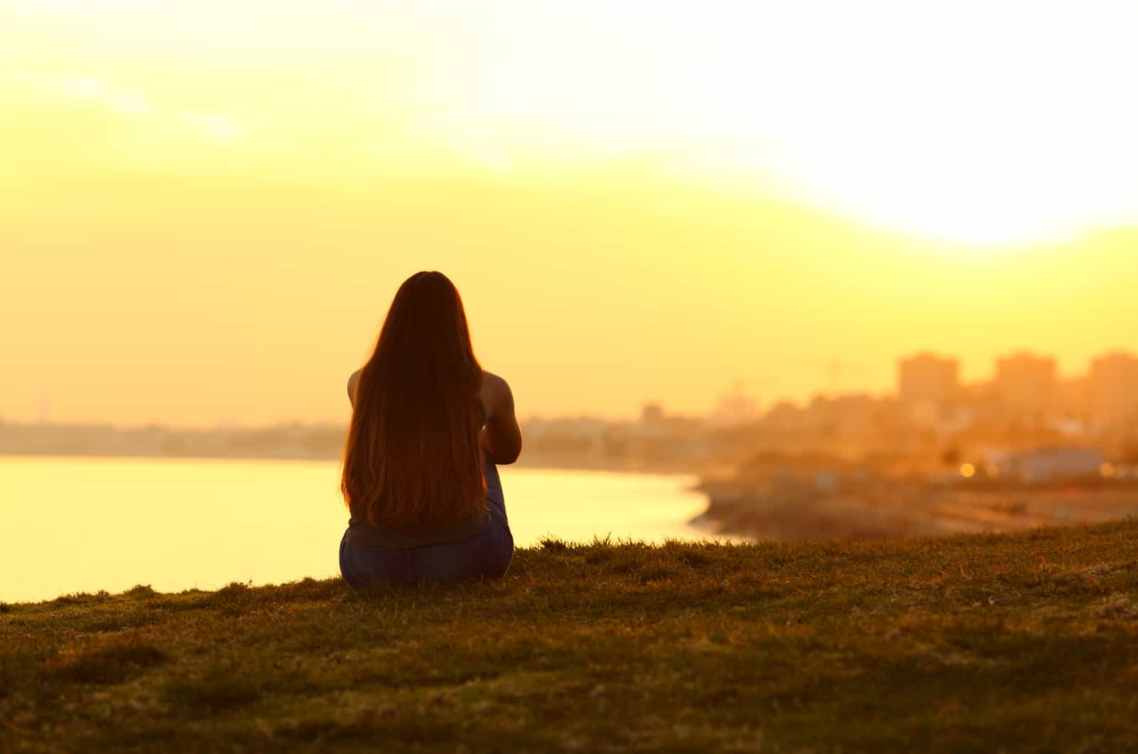 mujer sentada al aire libre mirando la puesta de sol