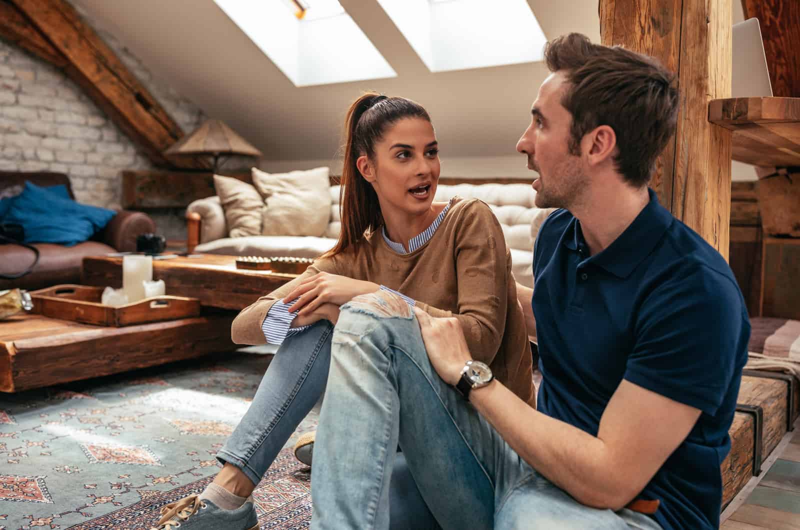 young couple is talking while sitting on floor of living room