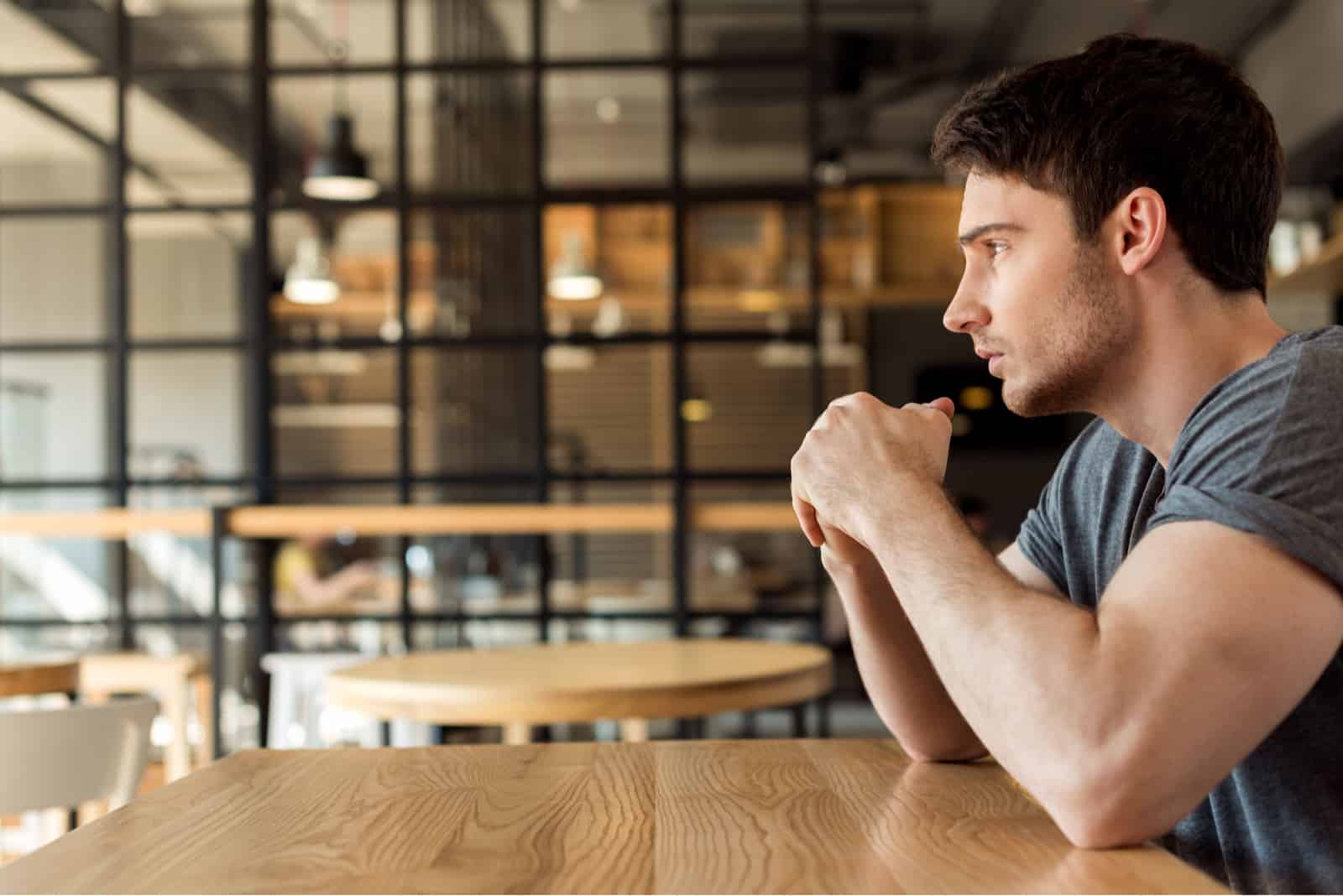 young man sitting in cafe thinking about something