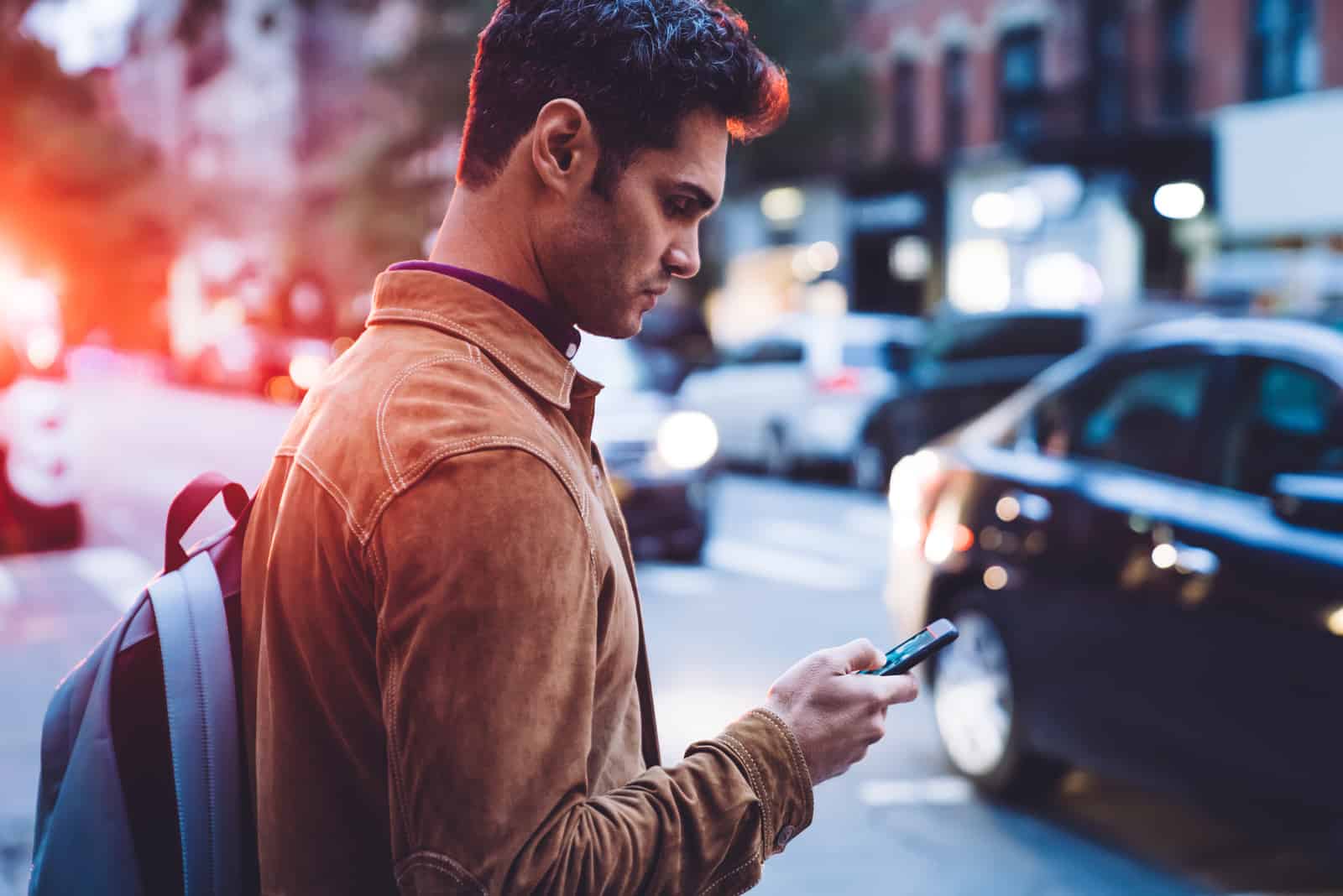 joven enviando un mensaje de texto mientras cruza la calle