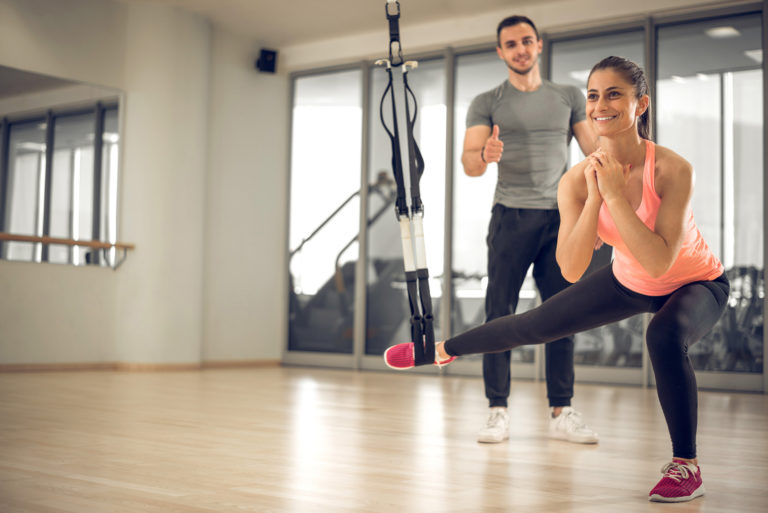 smiling woman exercising next to a coach