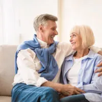 a smiling man hugged the woman as they sat on the couch